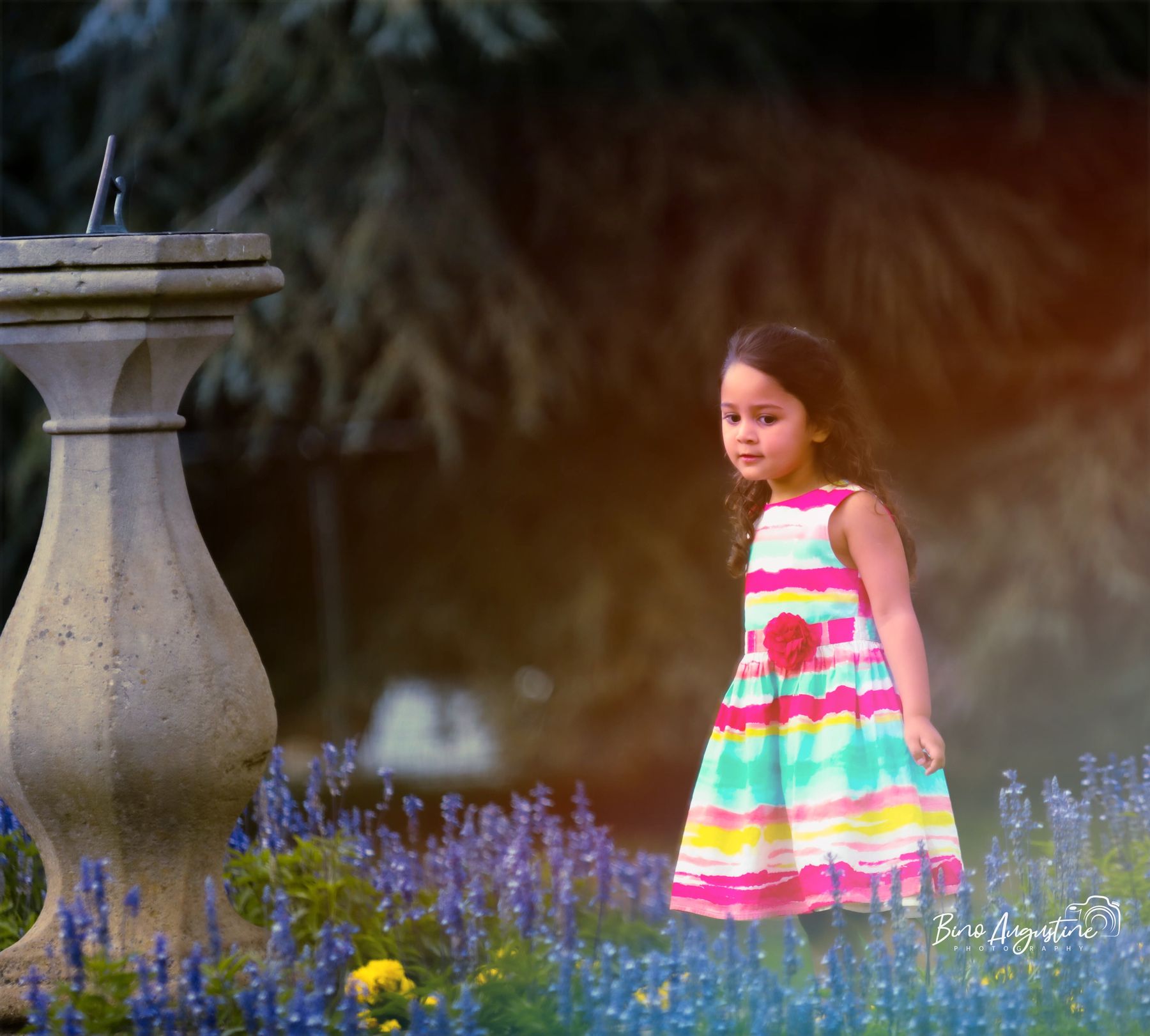 Little girl in a striped dress walking through a flower garden