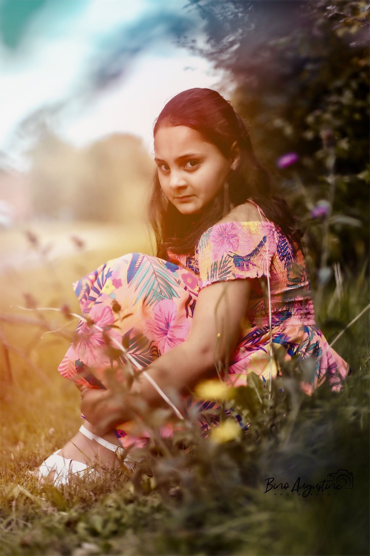 Girl sitting among wildflowers in soft summer light