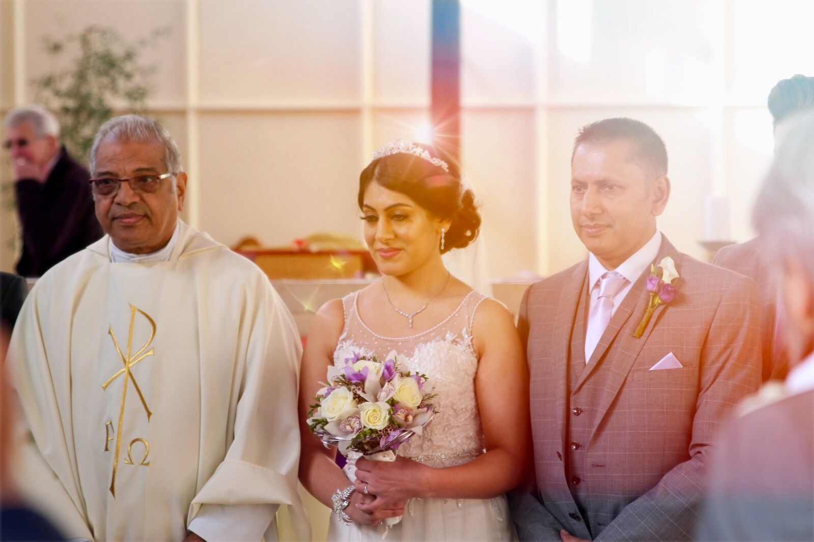 Bride smiling at the altar with the groom and priest