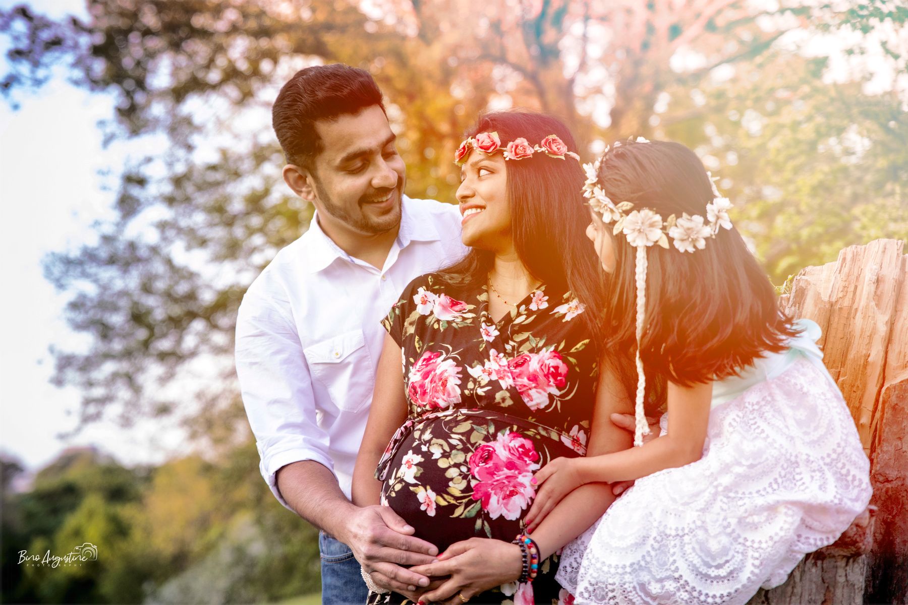 Expecting parents and their daughter in autumn sunlight